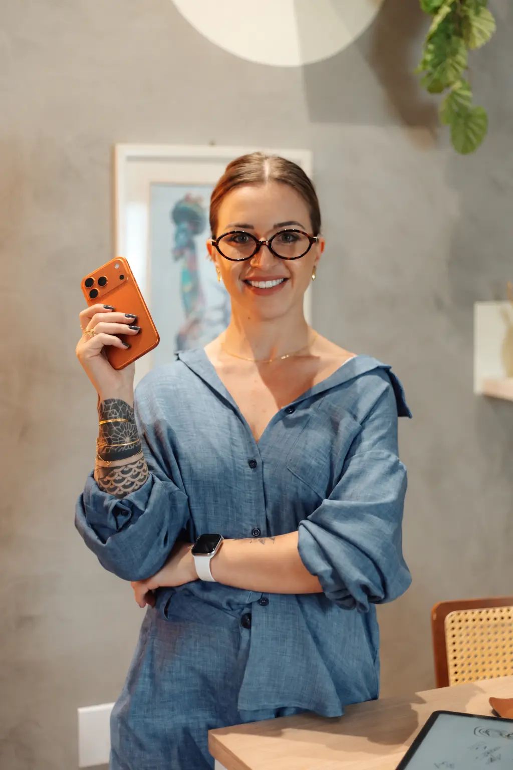 Isabela Ranú de camisa azul, de frente, segurando seu celular